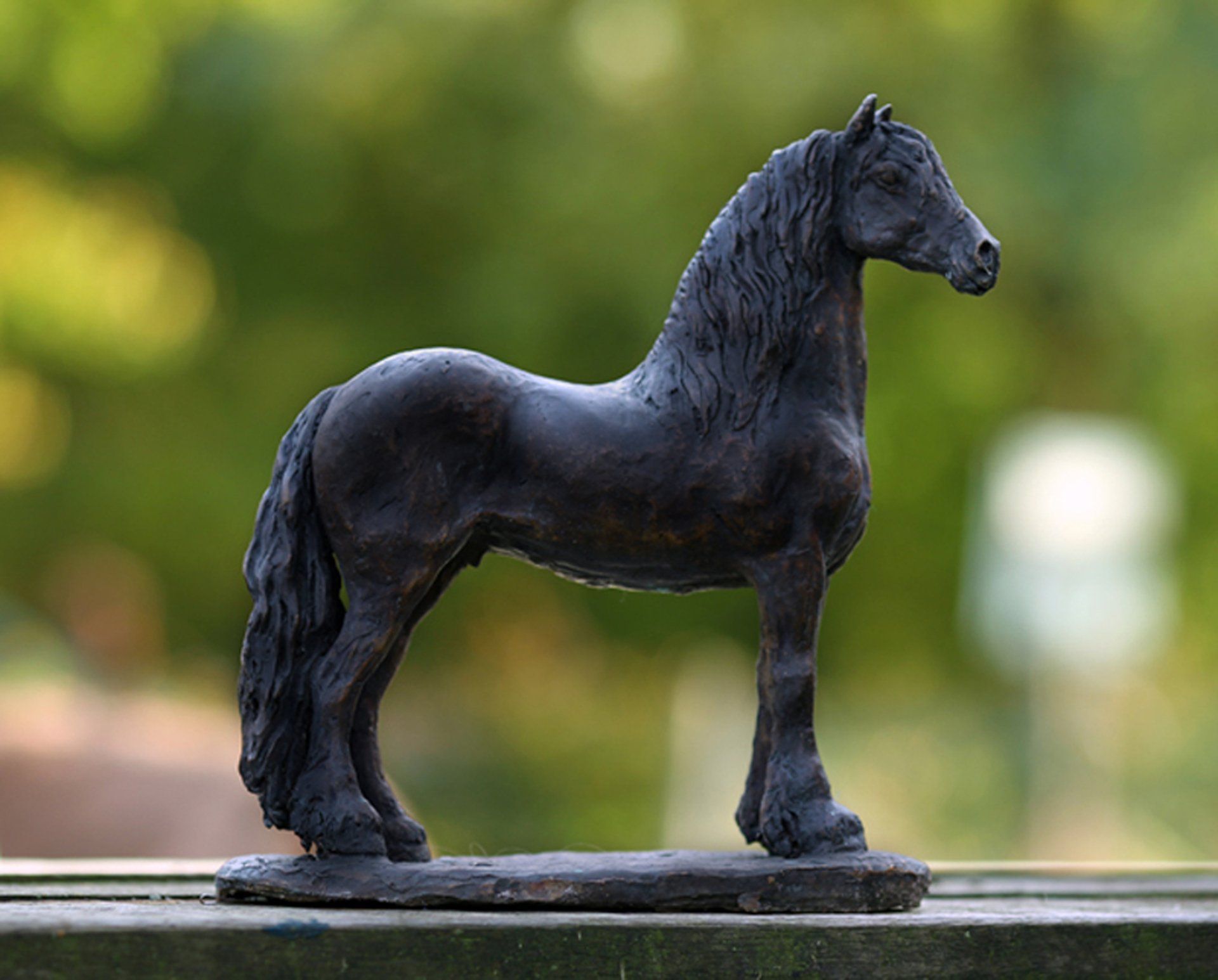 Een standbeeld van een zwart paard staand op een houten leuning