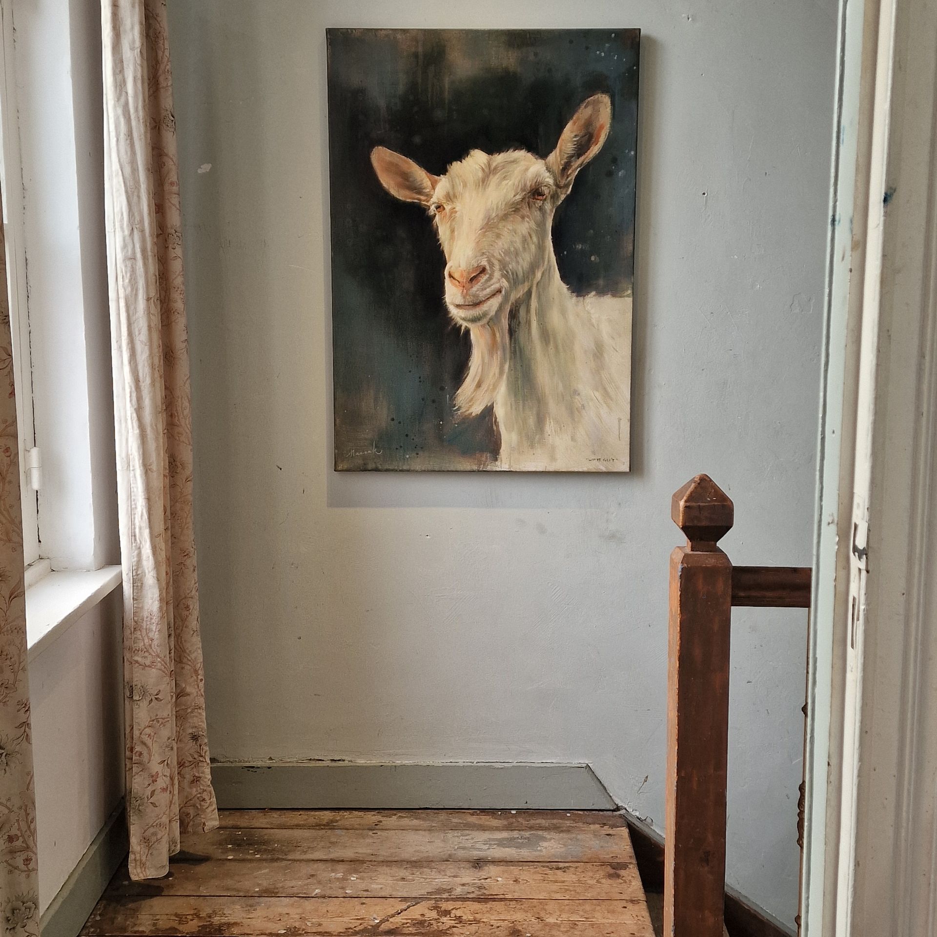Aan de muur hangt een schilderij van een geit