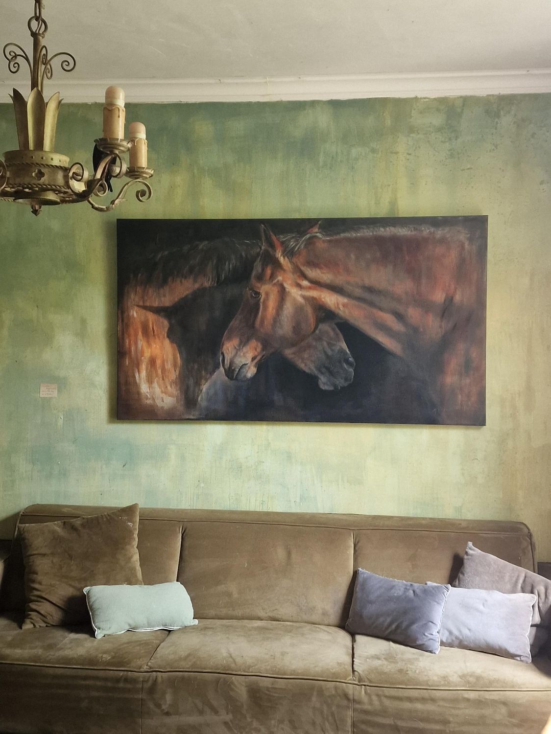 Een woonkamer met een bank en een schilderij van een paard aan de muur