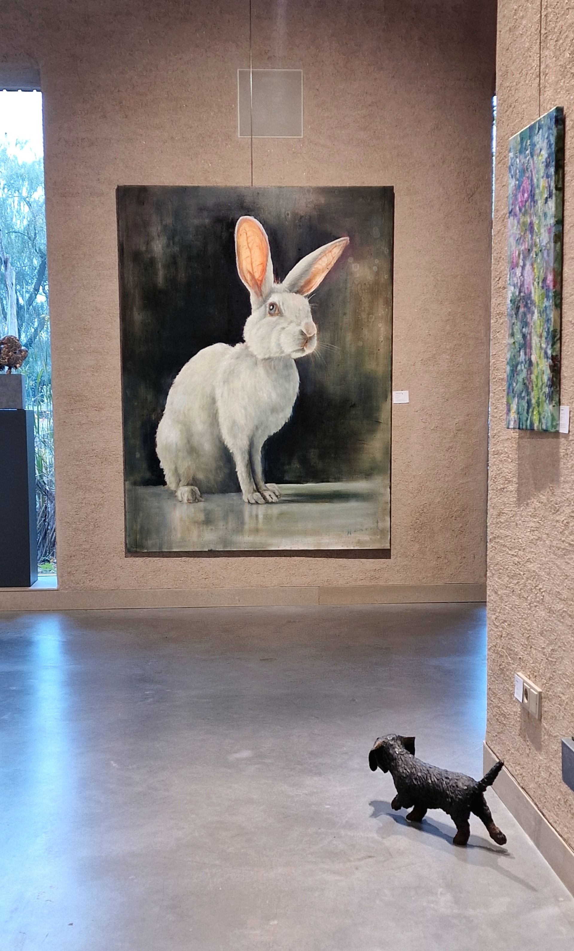 Een hond staat voor een schilderij van een wit konijn.