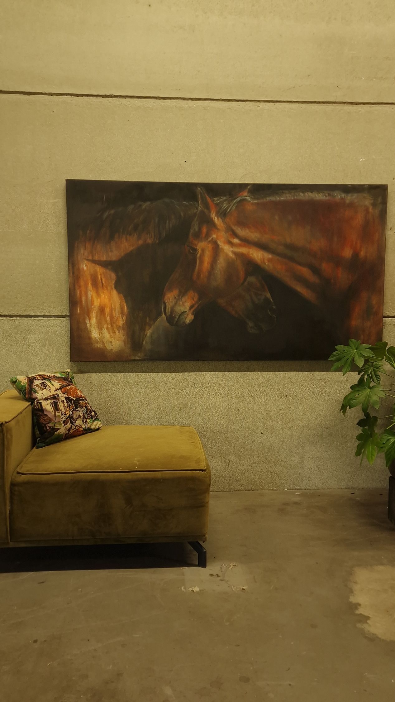 Moderne lobby met gele bank, bloemenkussen, potplant en groot donker abstract kunstwerk aan de muur.