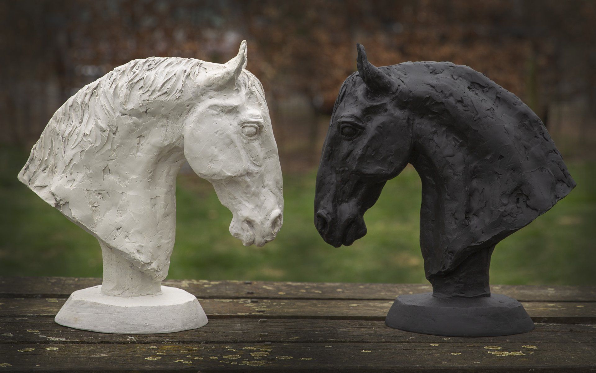 Twee beelden van paardenkoppen staan ​​op een houten tafel.