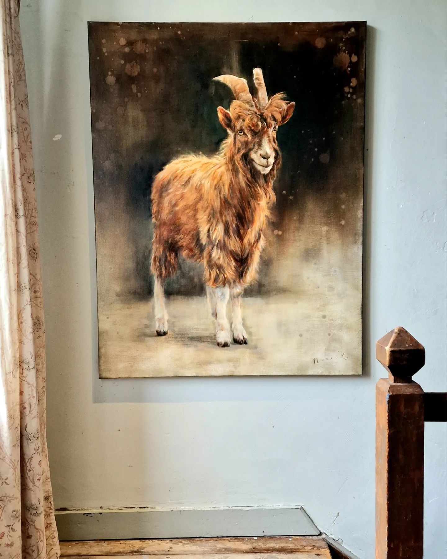 Een schilderij van een geit met horens hangt aan een muur