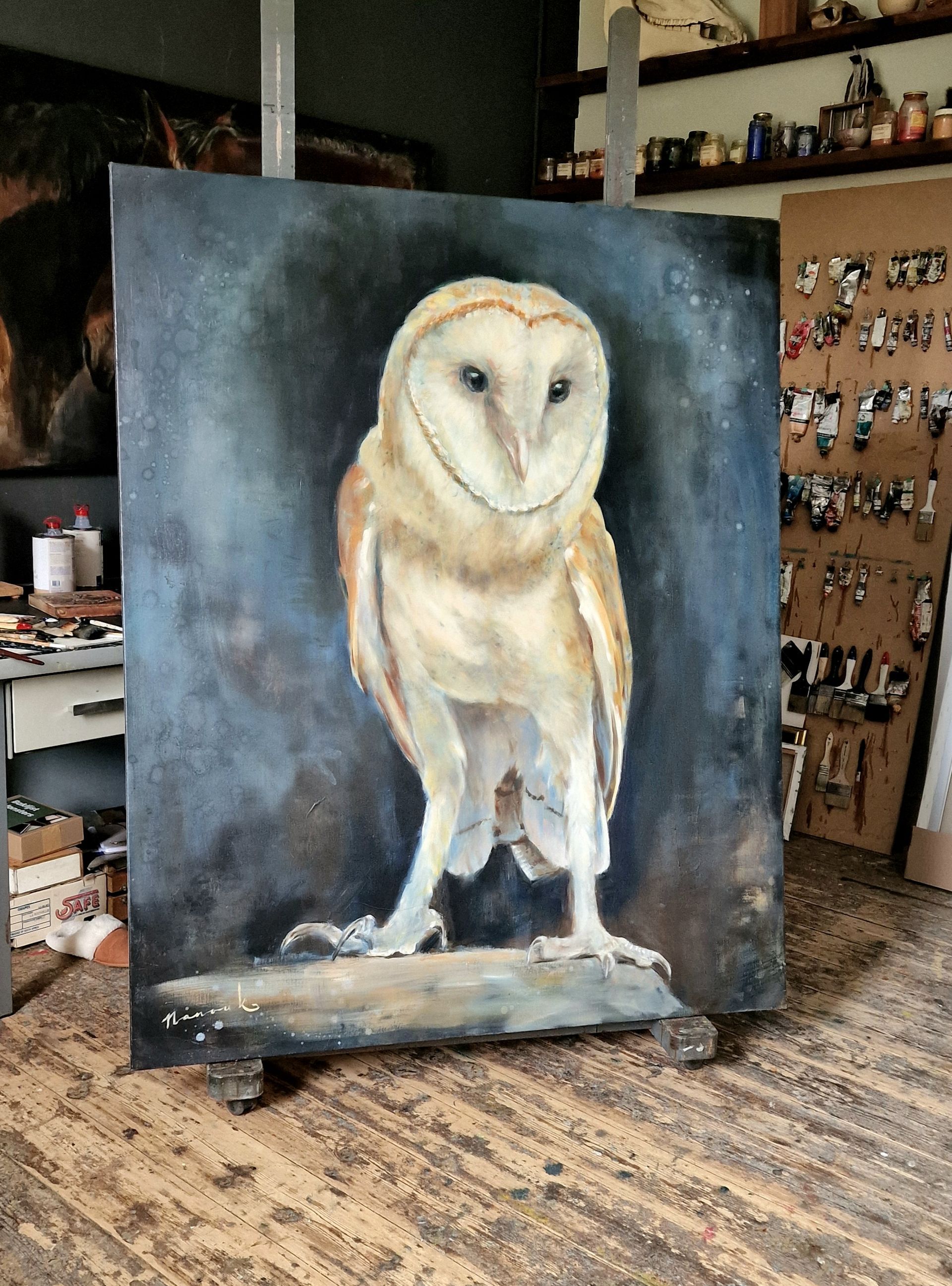 Een groot schilderij van een uil staat op een ezel