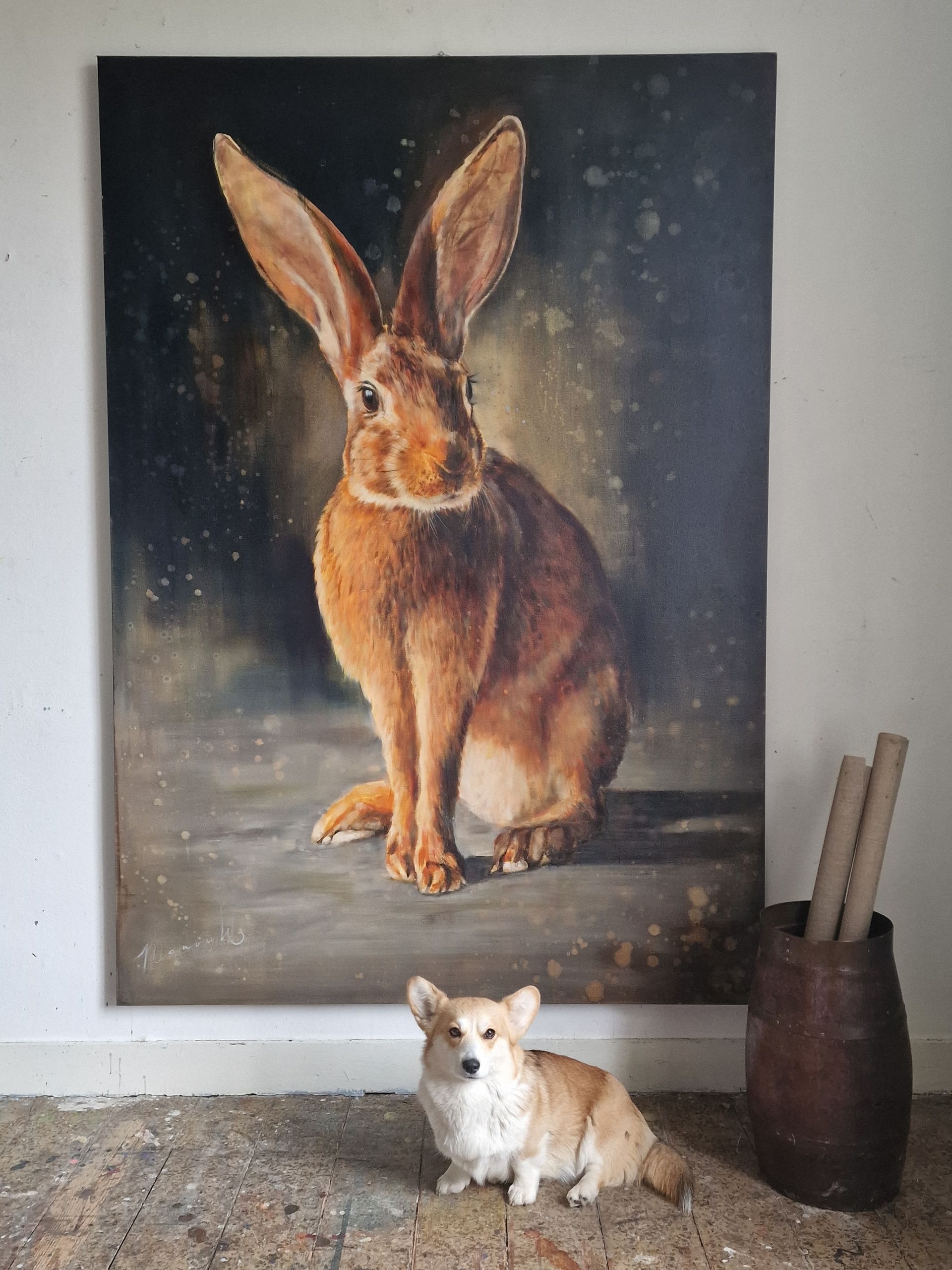 Een hond zit voor een schilderij van een konijn