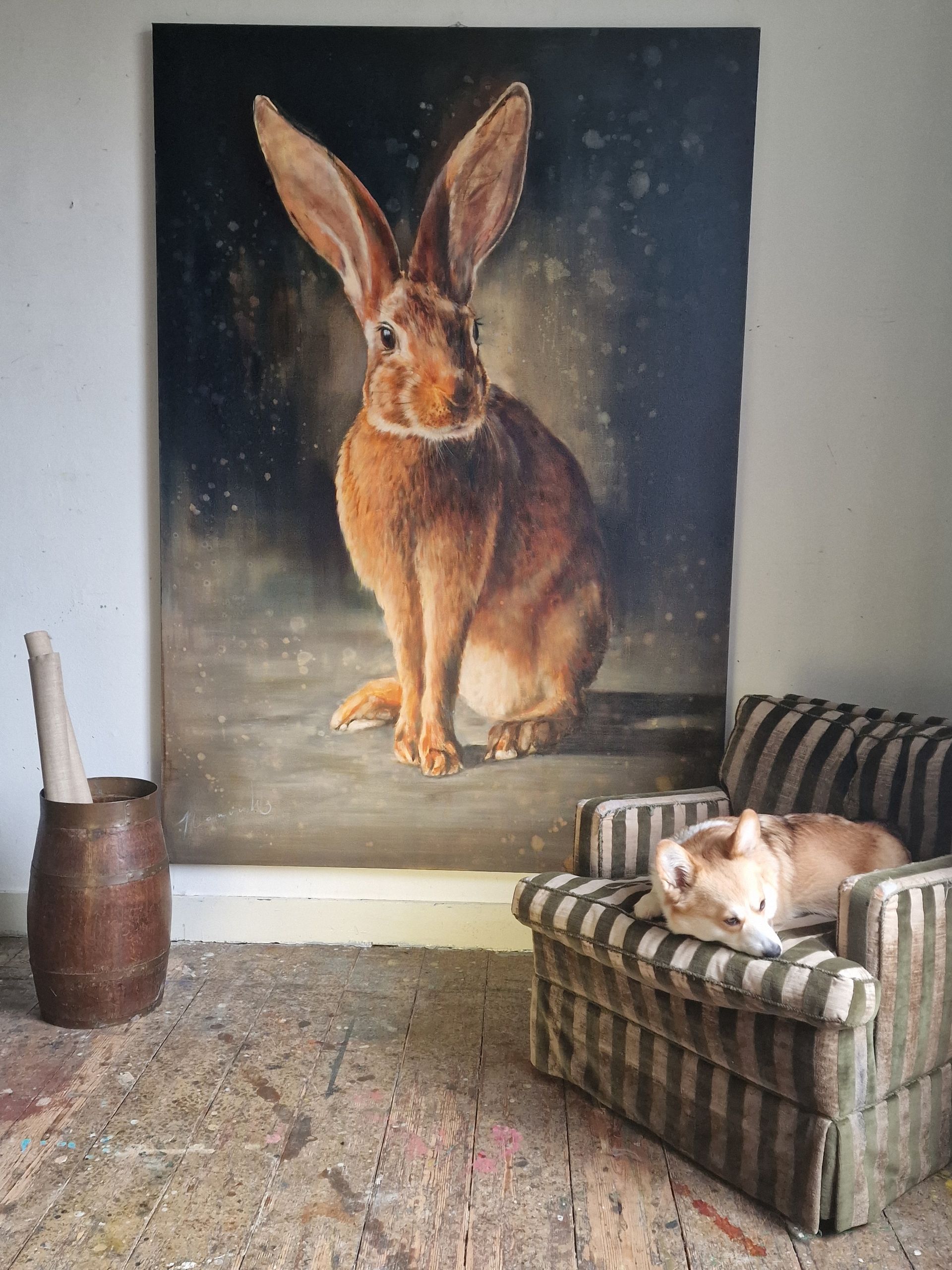 Een schilderij van een konijn hangt aan een muur boven een bank
