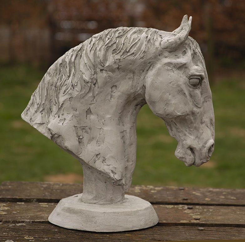 Een standbeeld van een paardenhoofd zit op een houten tafel