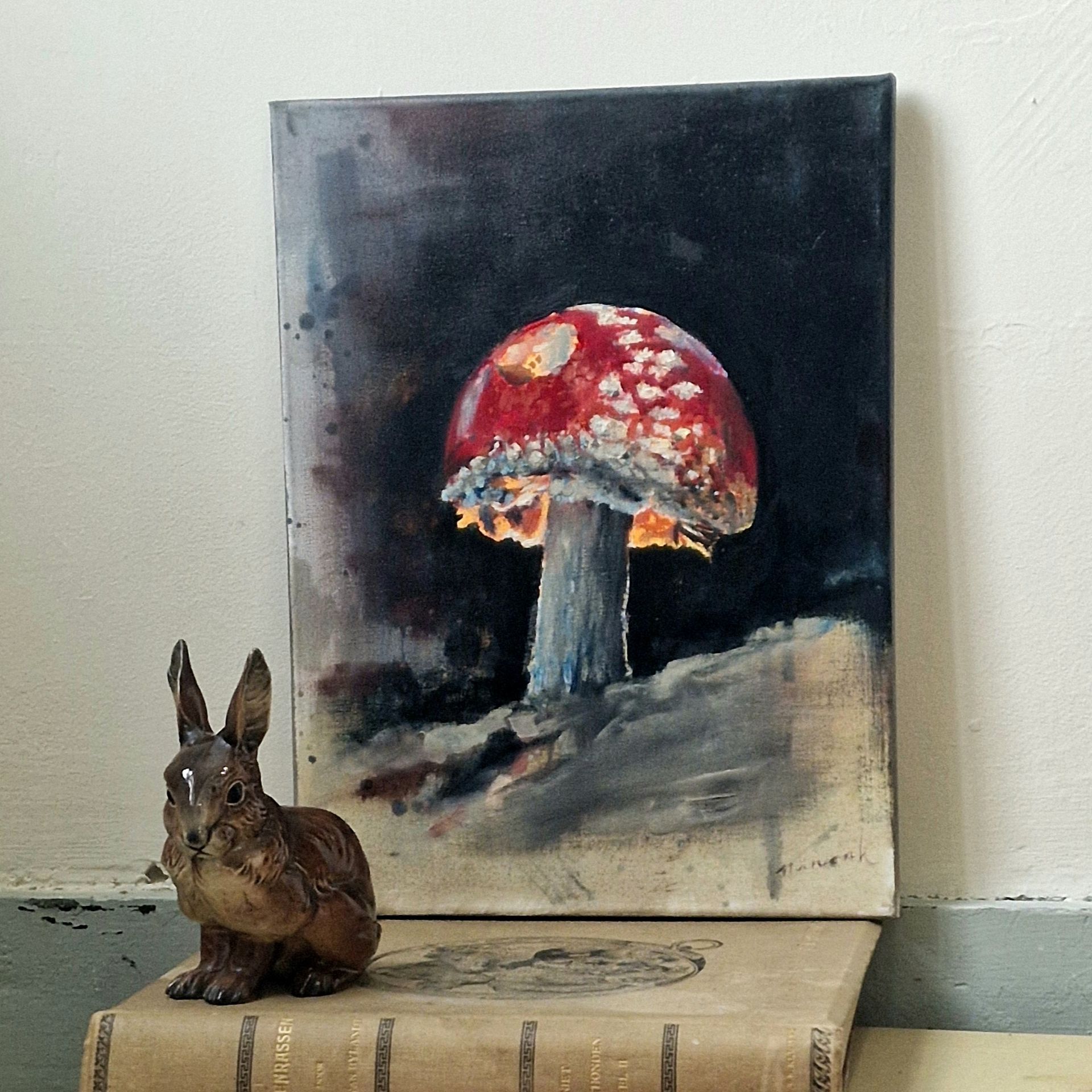 Een schilderij van een rode paddenstoel met witte vlekken , konijnenbeeldje