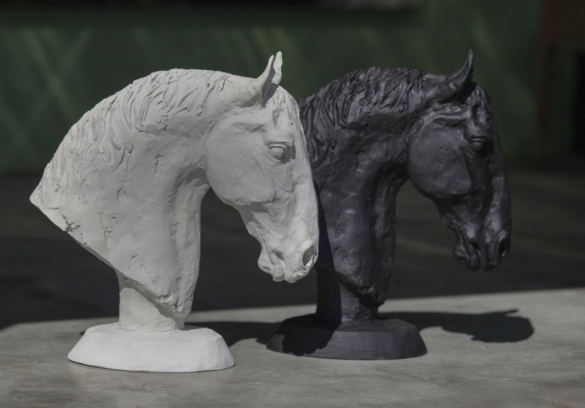 Twee paardenbeelden zitten naast elkaar op een tafel.