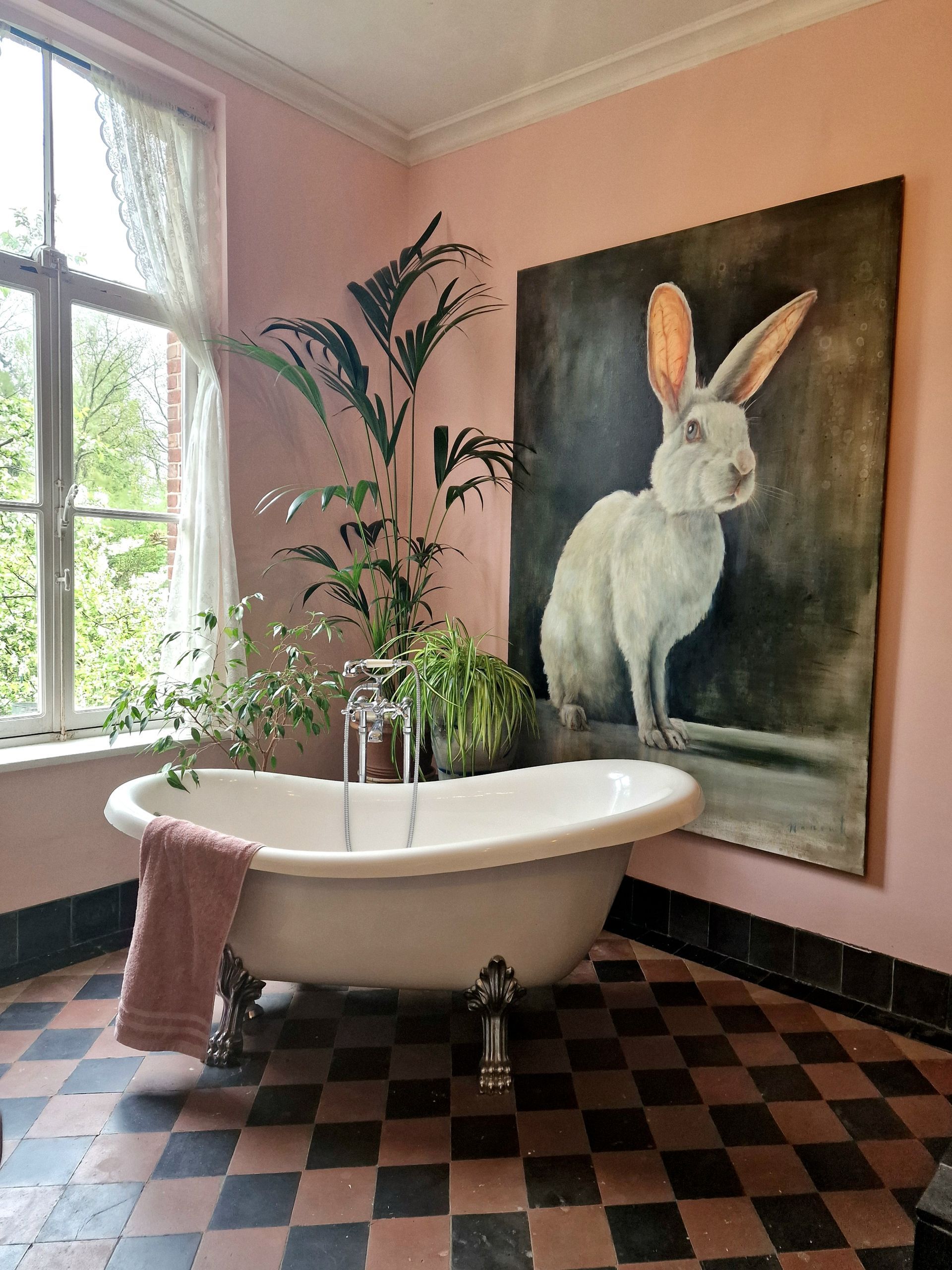 Een badkamer met een bad en een schilderij van een konijn aan de muur.