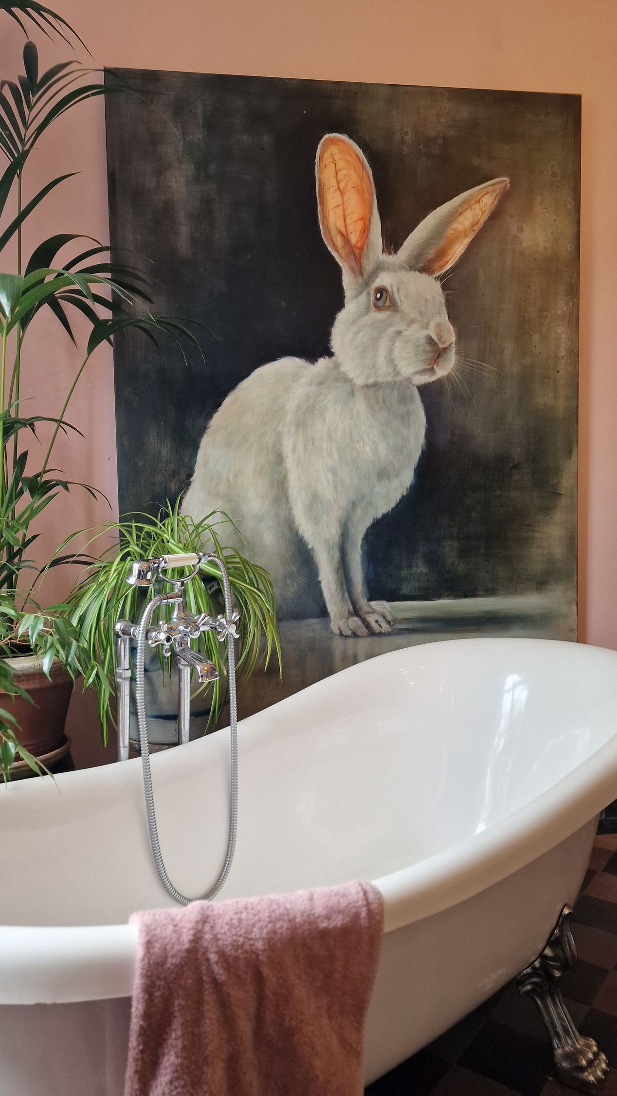 Een badkuip in een badkamer met een schilderij van een konijn aan de muur erachter.