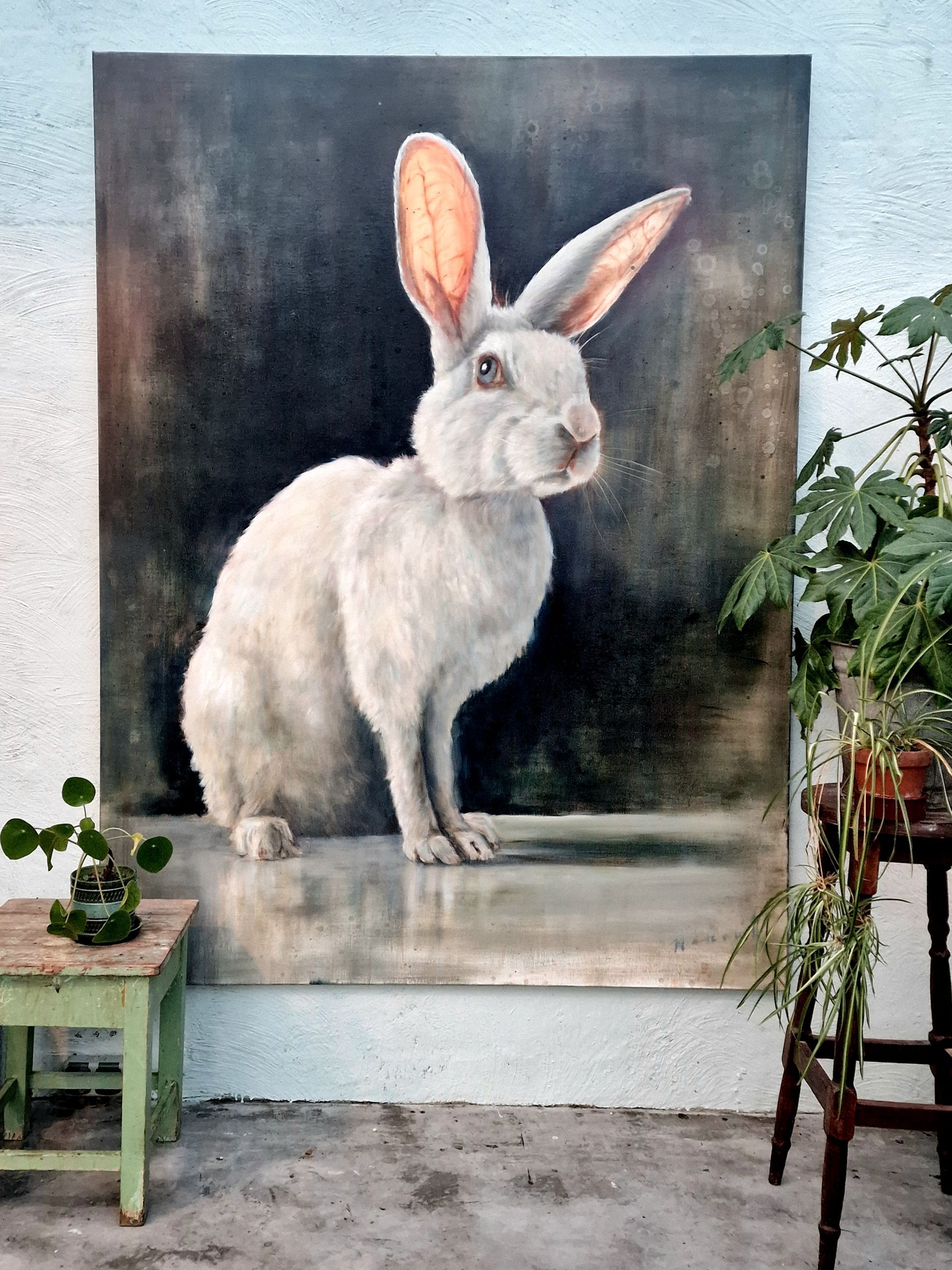 Er hangt een groot schilderij van een wit konijn aan de muur.