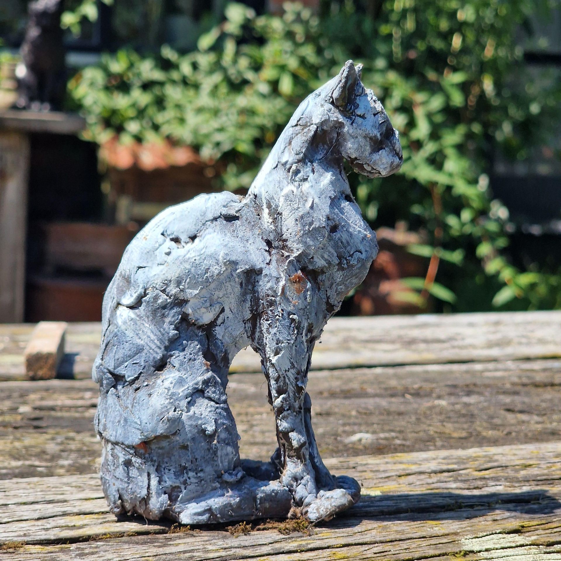 Een standbeeld van een kat zit op een houten tafel.