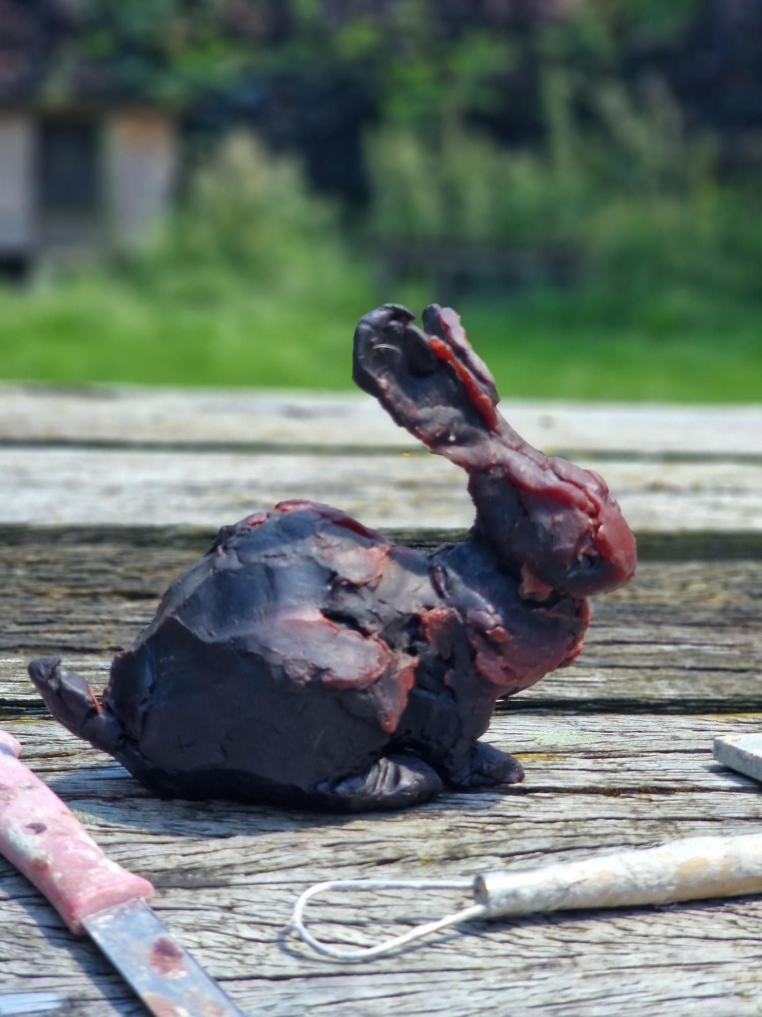 Een beeld van een konijn zit op een houten tafel.