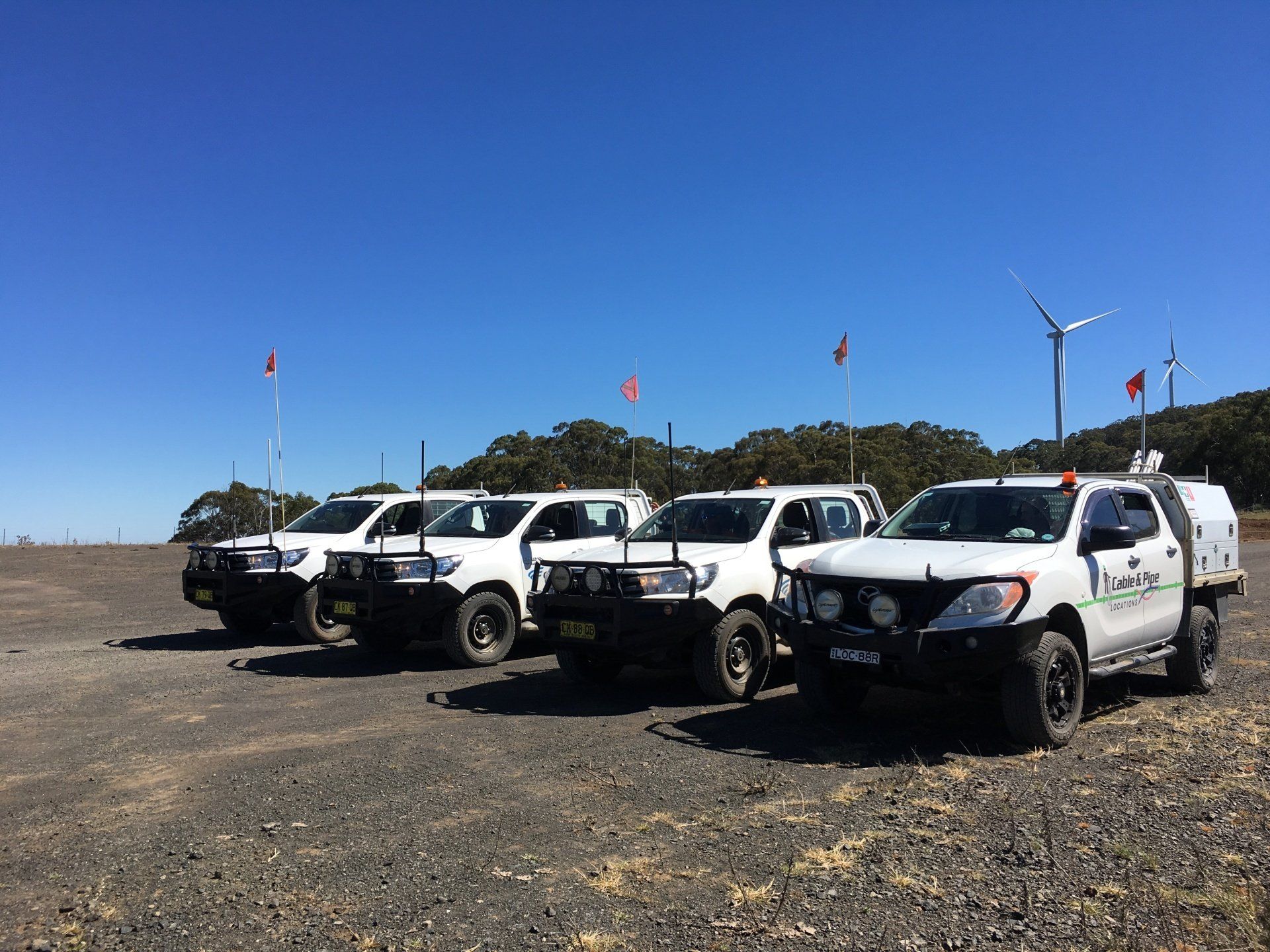 A Row of White Trucks Are Parked in A Dirt Field — Cable & Pipe Locations in Inverell, NSW