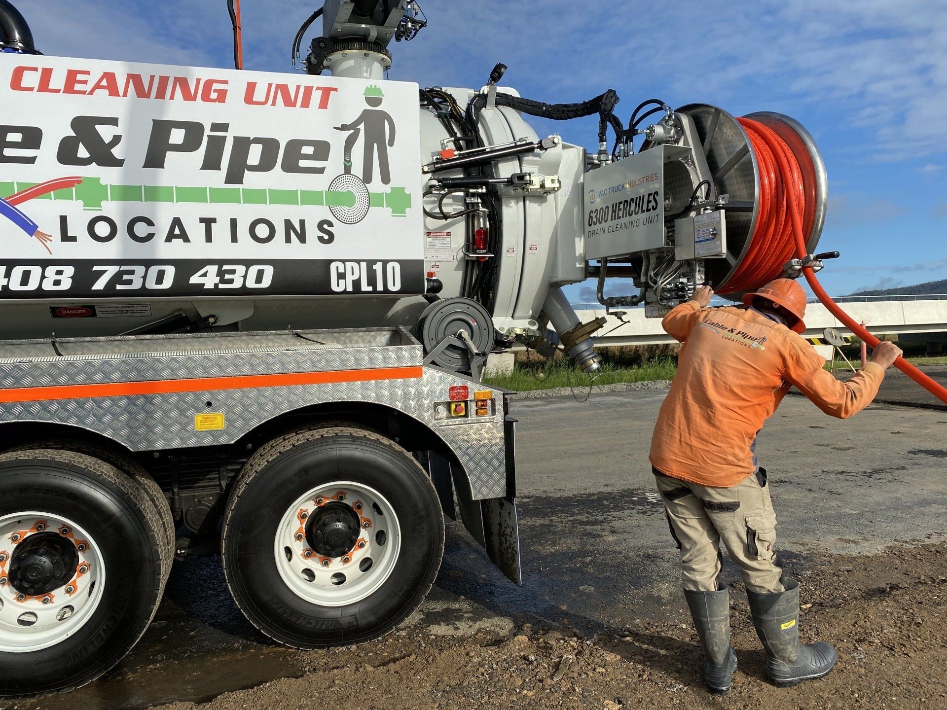 Technician operating a high-pressure drain cleaning unit mounted on a Cable & Pipe Locations truck.