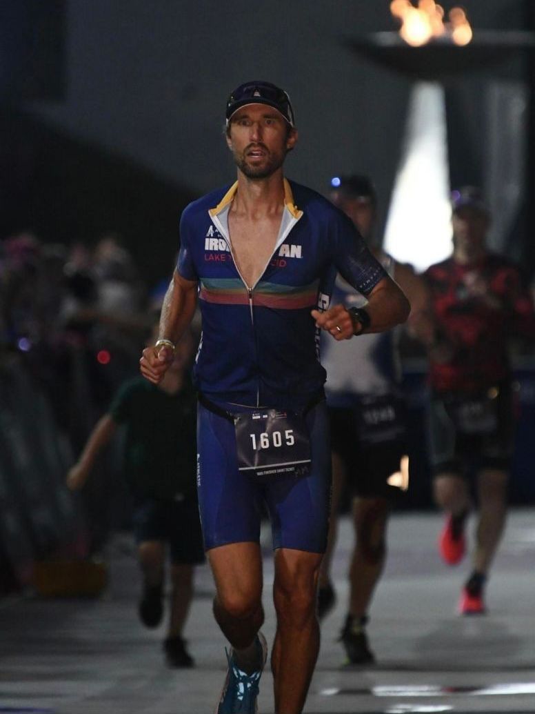 A man in a blue shirt is running with the number 16 05 on his bib