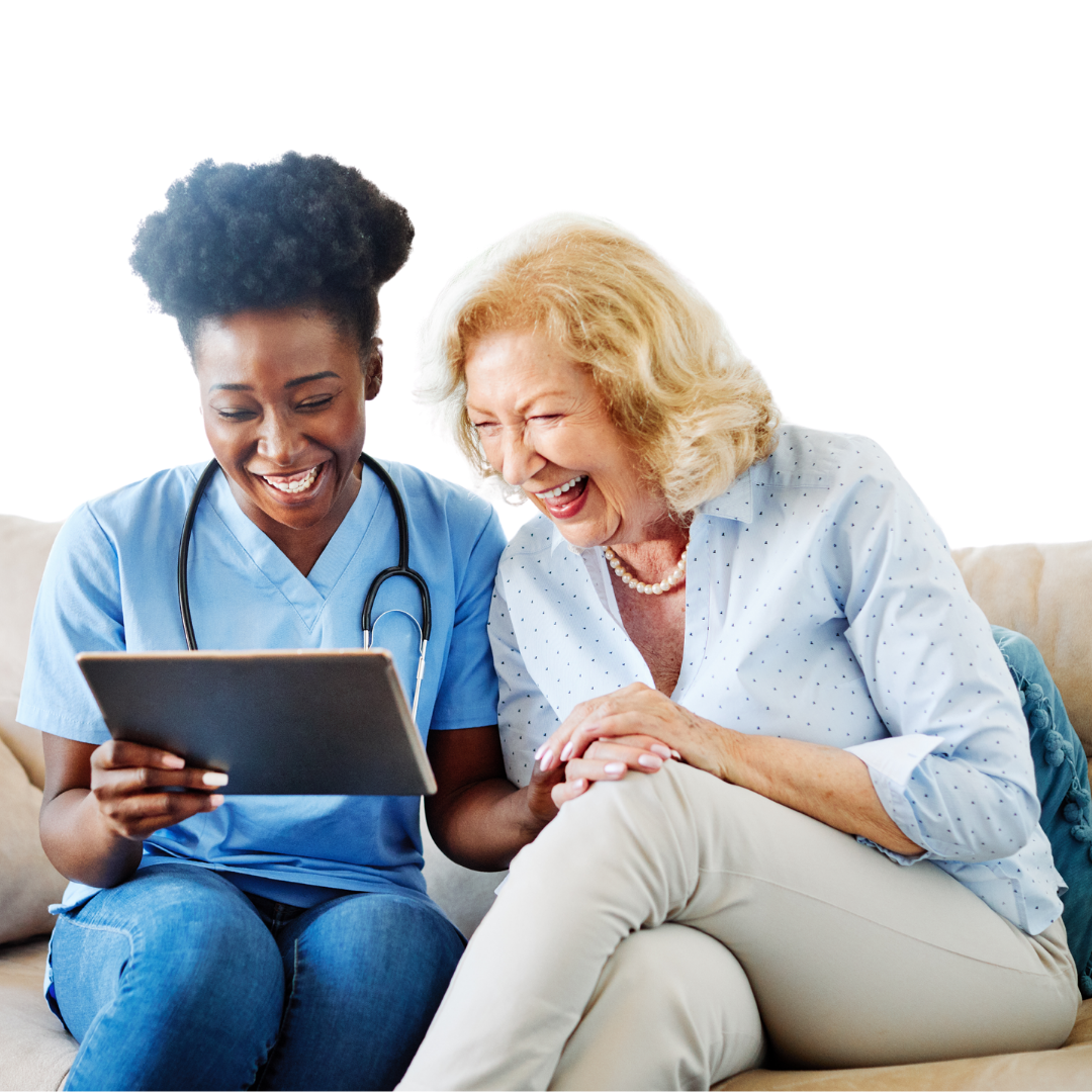 Nurse and elderly woman smiling, looking at tablet on a couch.