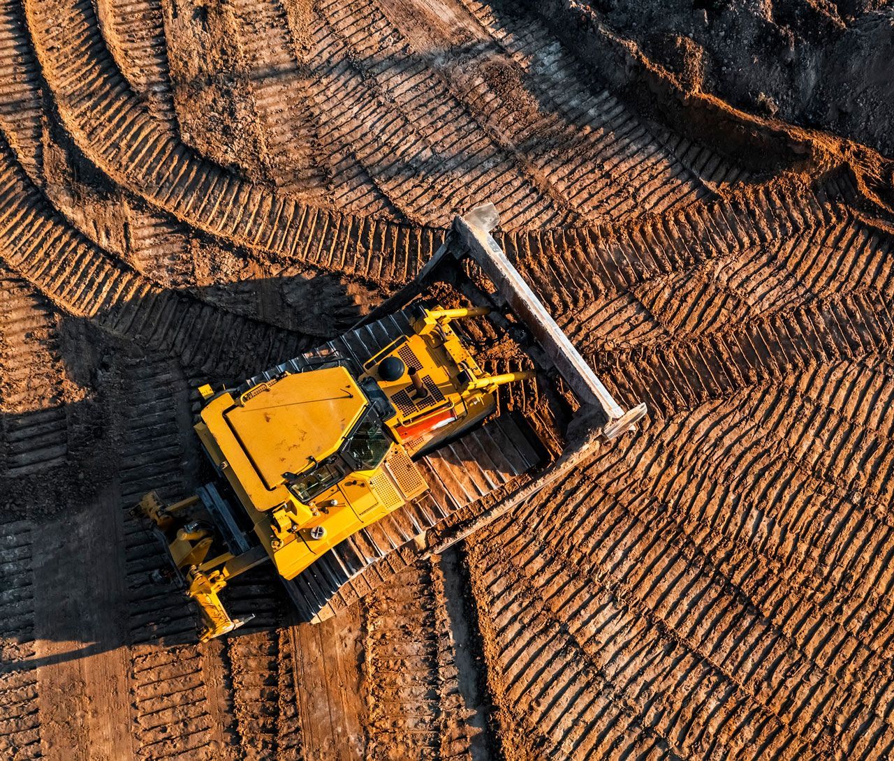 An aerial view of a bulldozer moving dirt on a construction site.