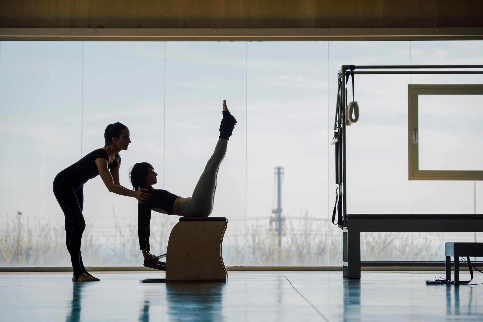 Una donna aiuta un'altra donna a fare pilates in palestra.