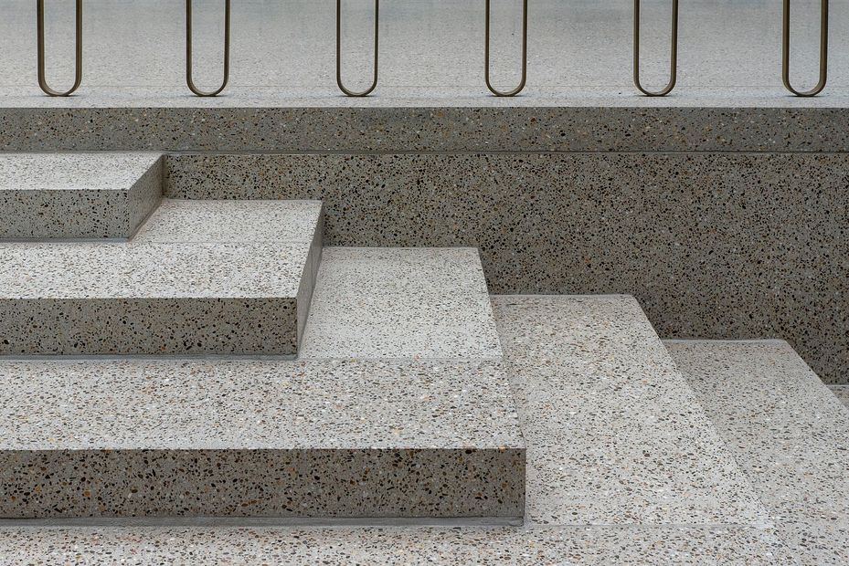 Concrete steps with textured gray walls and curved metal railings above.