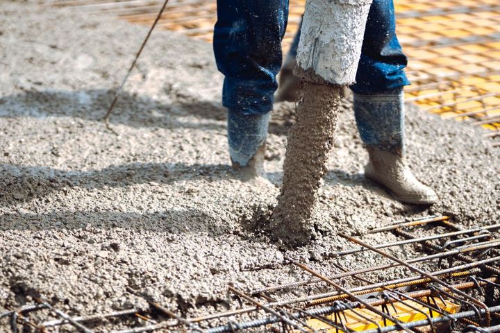 Workers pouring concrete over rebar at a construction site