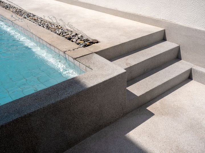Poolside steps beside a turquoise swimming pool and stone deck
