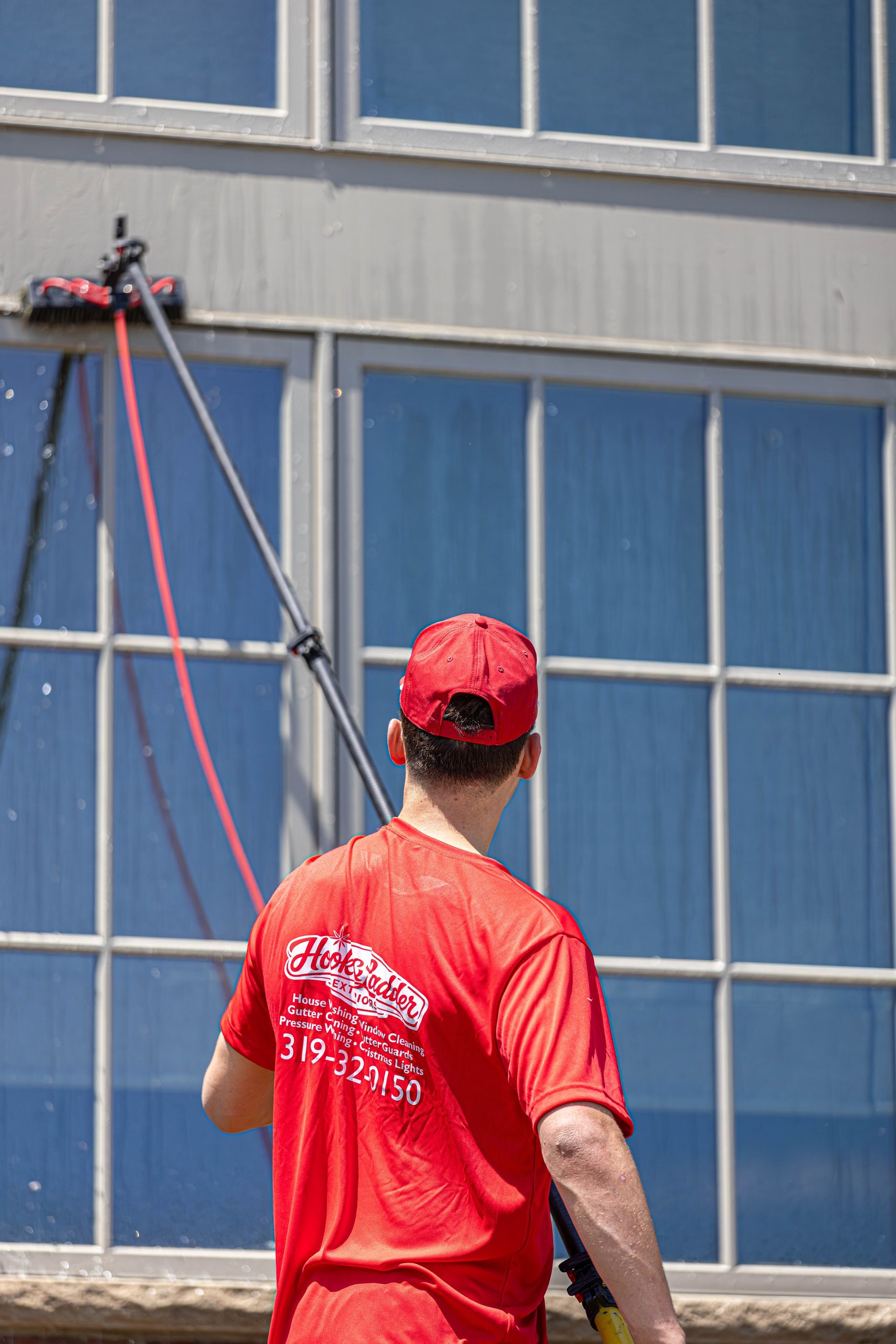 Worker in red shirt and cap using a rope access system on a building exterior