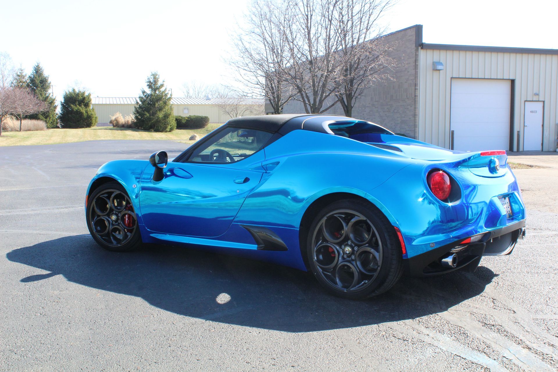 Blue sports car parked outside an industrial building on a sunny day