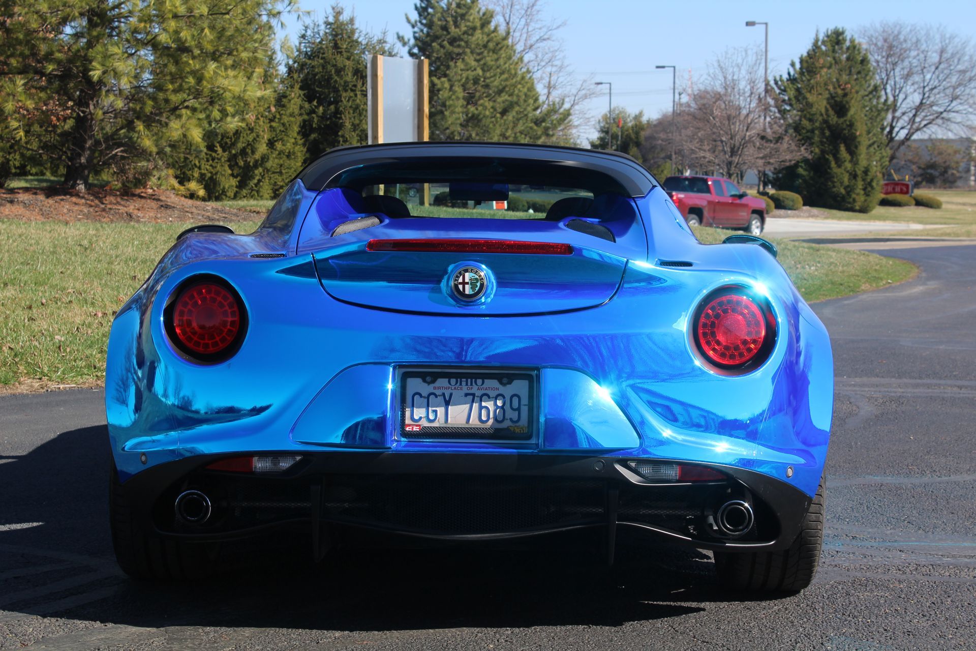 Rear view of a blue sports car parked outdoors on a sunny road