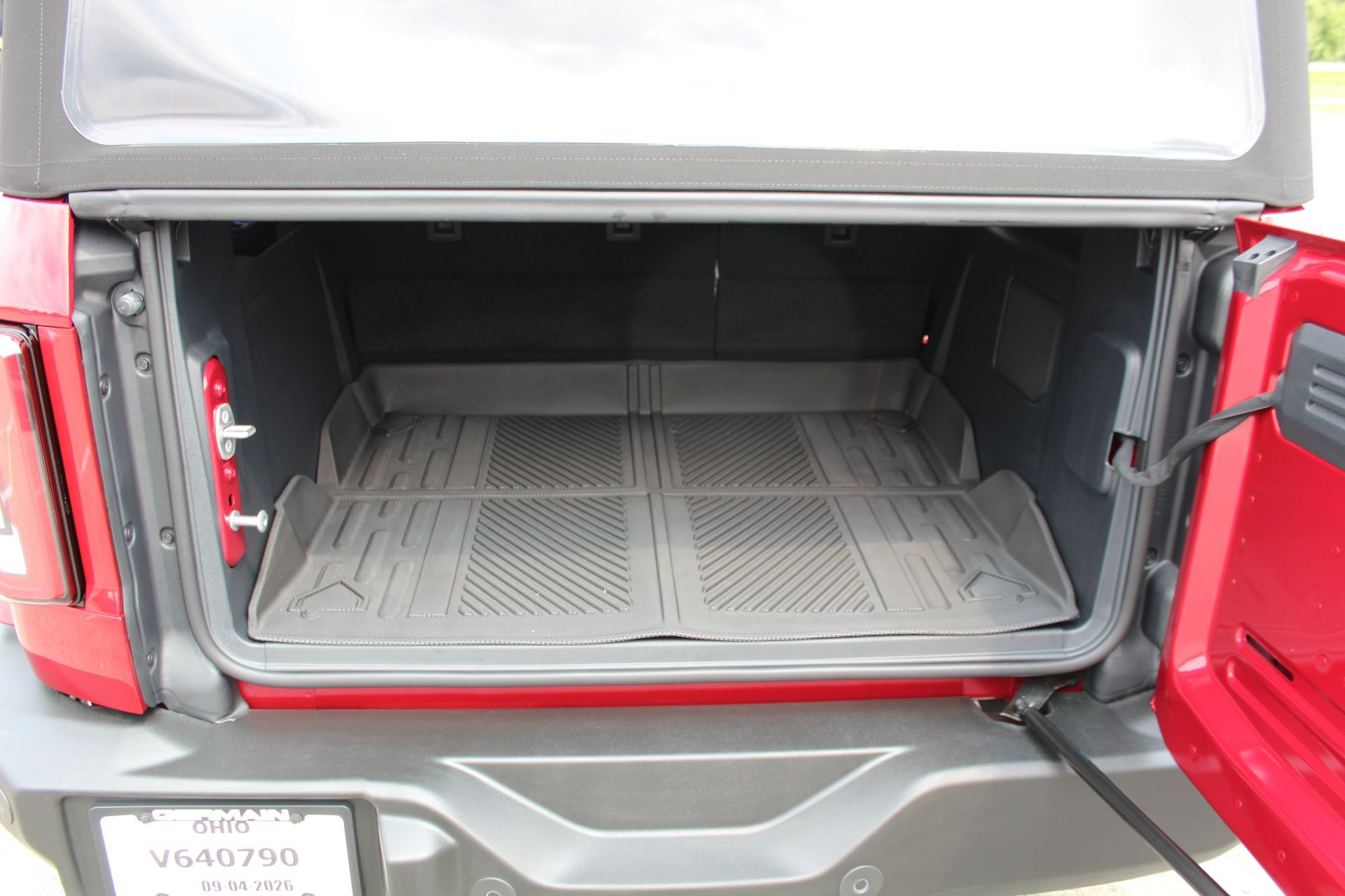 Open red SUV trunk with empty cargo area and black floor mats