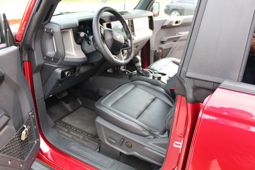 Open car door showing black leather front seat and dashboard in a red vehicle