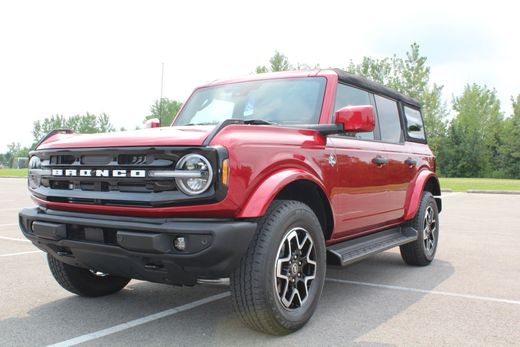 Red Ford Bronco SUV parked in a lot, front-left view, with black trim and off-road tires.