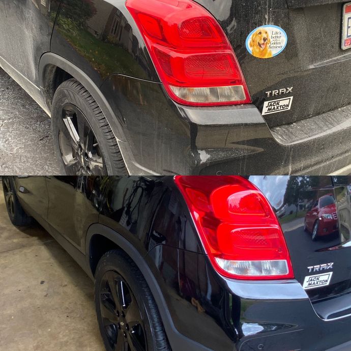 Black car parked indoors, rear and side view, with visible body damage and reflections on the paint.