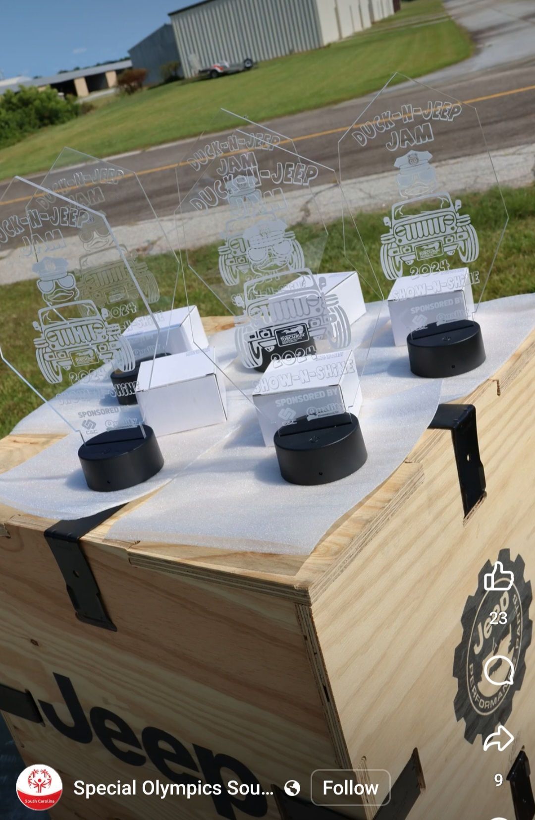 A wooden box filled with trophies and a jeep logo.