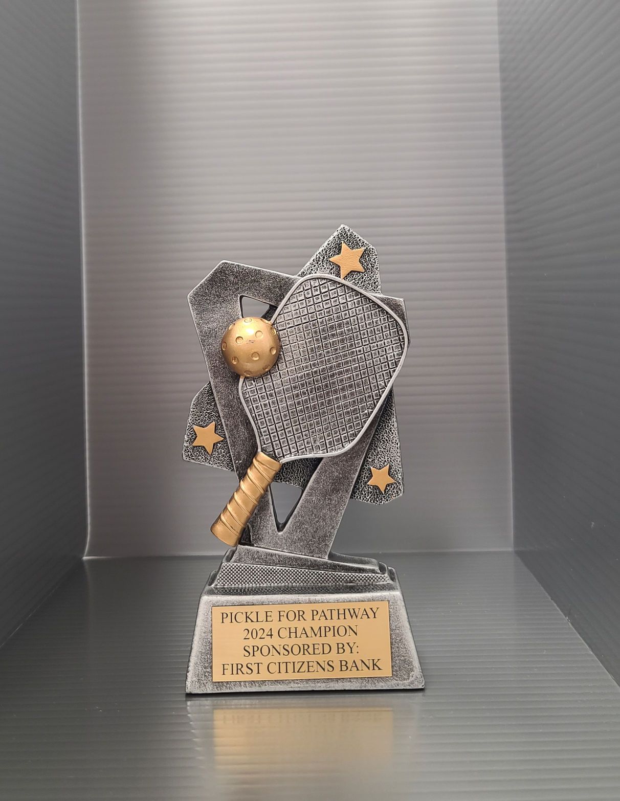A ping pong trophy is sitting on a shelf.