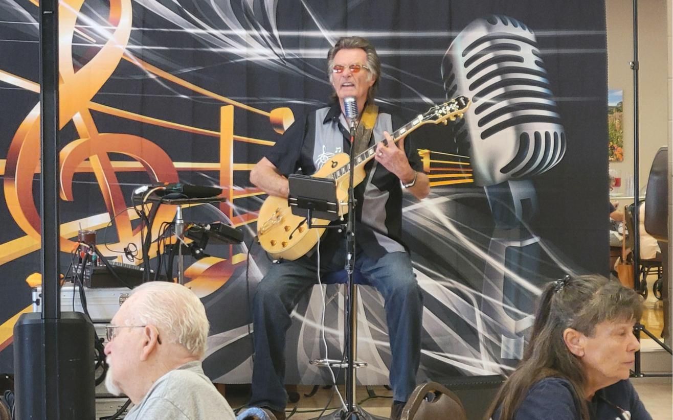 Kenny Laursen singing and playing guitar on a stage