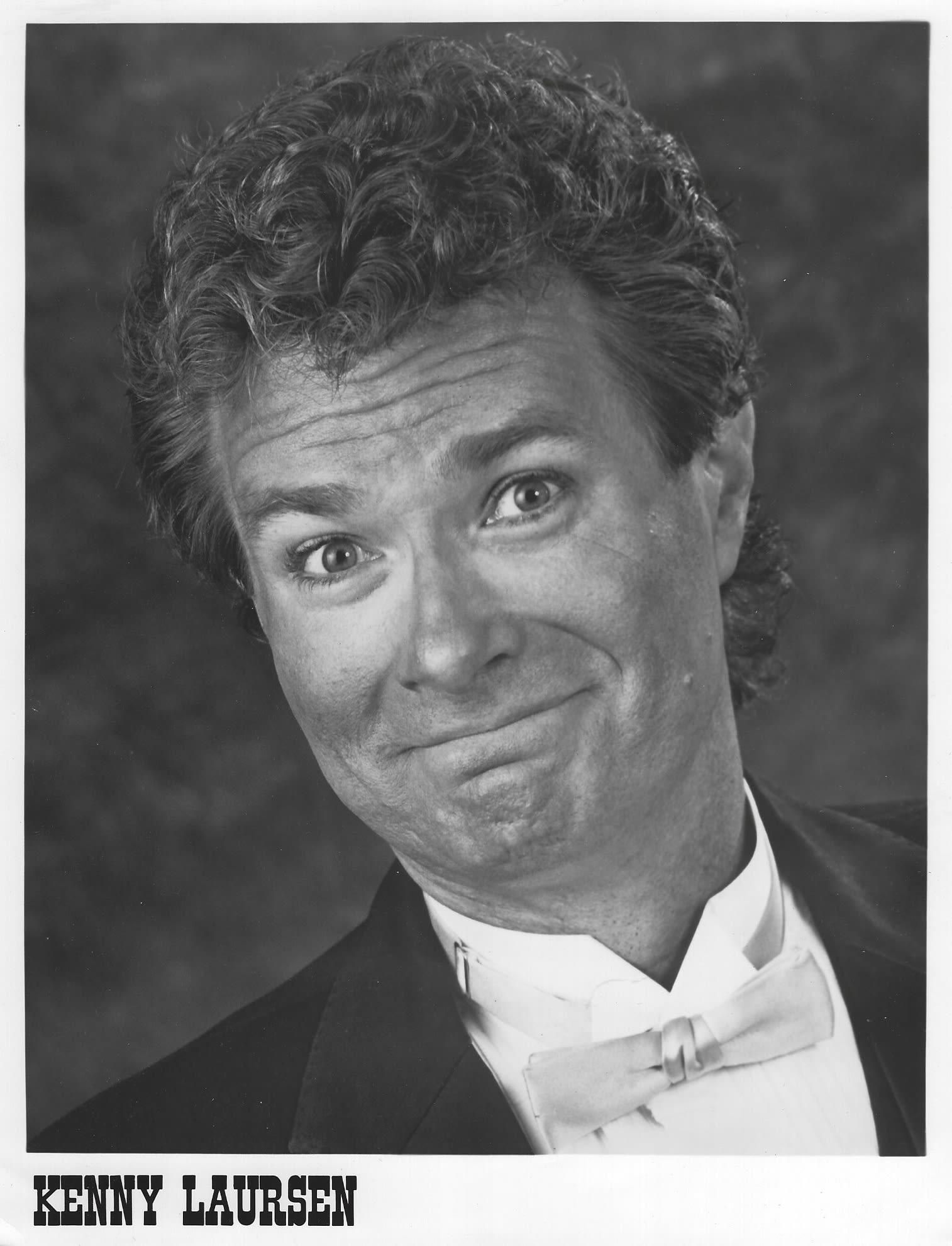 Black-and-white portrait of a smiling man in a tuxedo and bow tie, with the name “Kenny Lauren” below.
