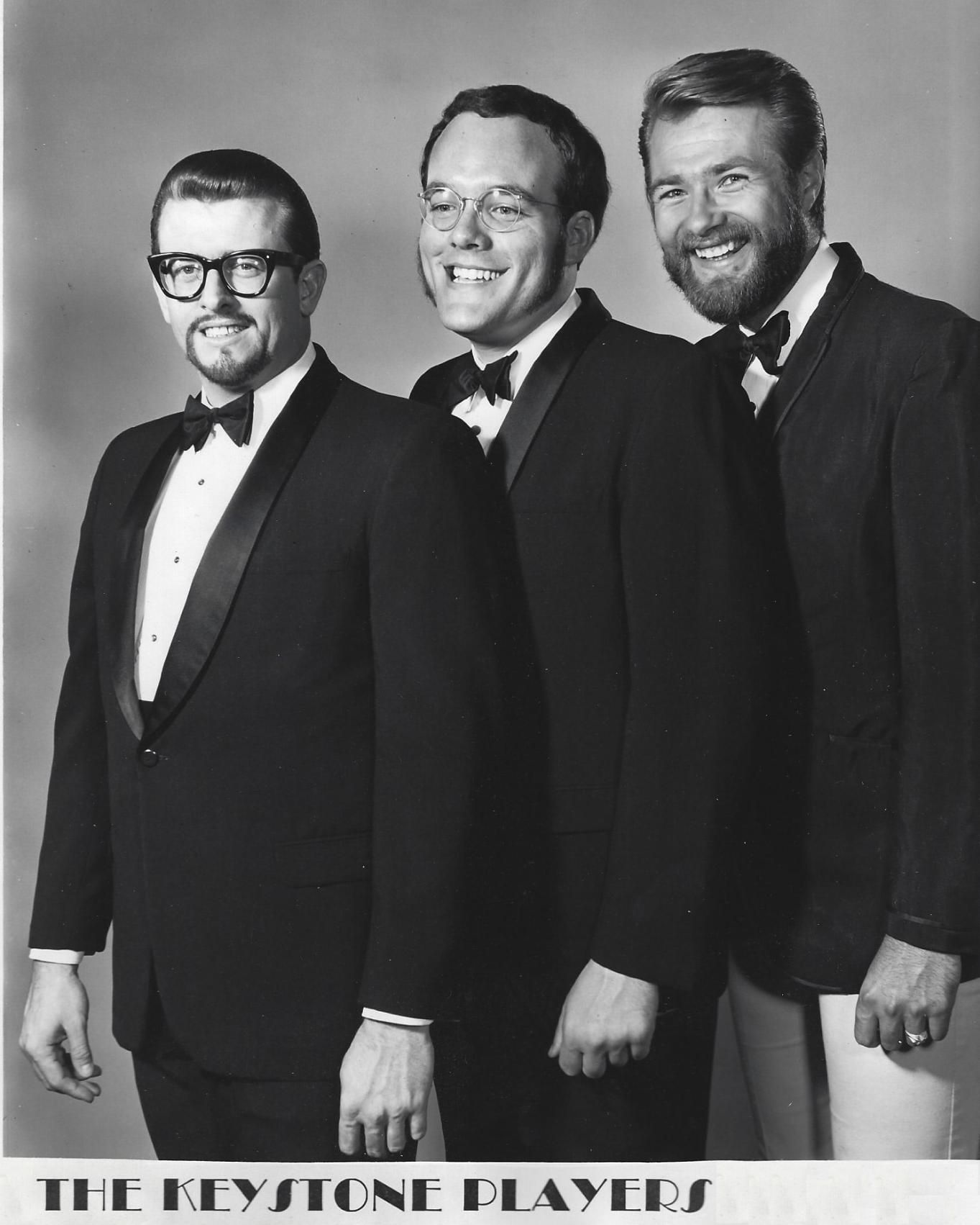 Three men in tuxedos pose smiling for a black-and-white portrait, with “THE KEYSTONE PLAYED” at the bottom.