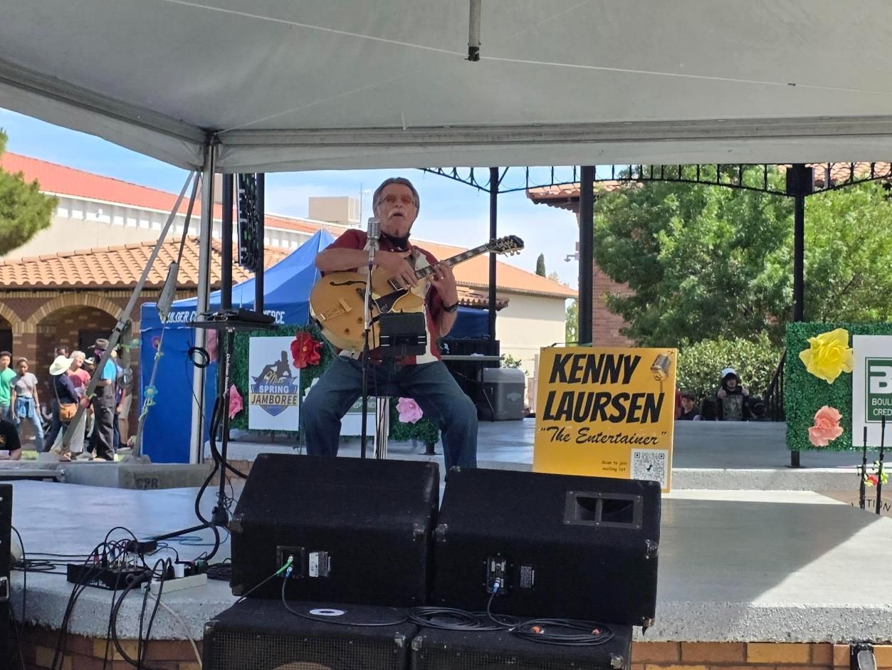 Kenny Laursen  performing on an outdoor stage under a canopy