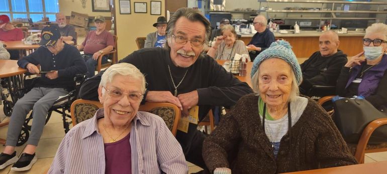 Three smiling people seated in a community room