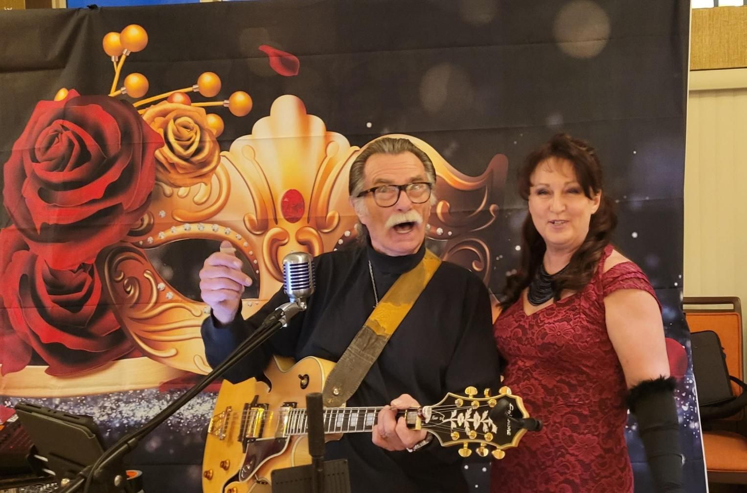Two people posing with a guitar onstage