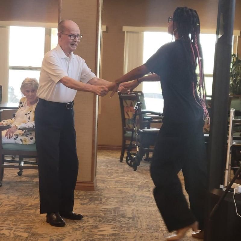 Two people holding hands and dancing in a carpeted room