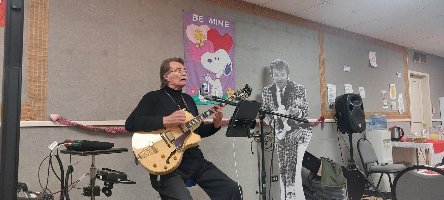 Kenny Laursen playing electric guitar beside his standee