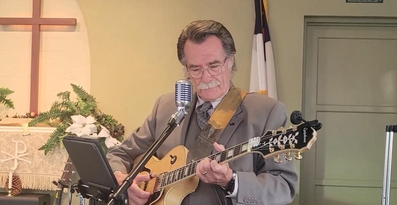 Kenny Laursen  playing guitar and singing into a microphone