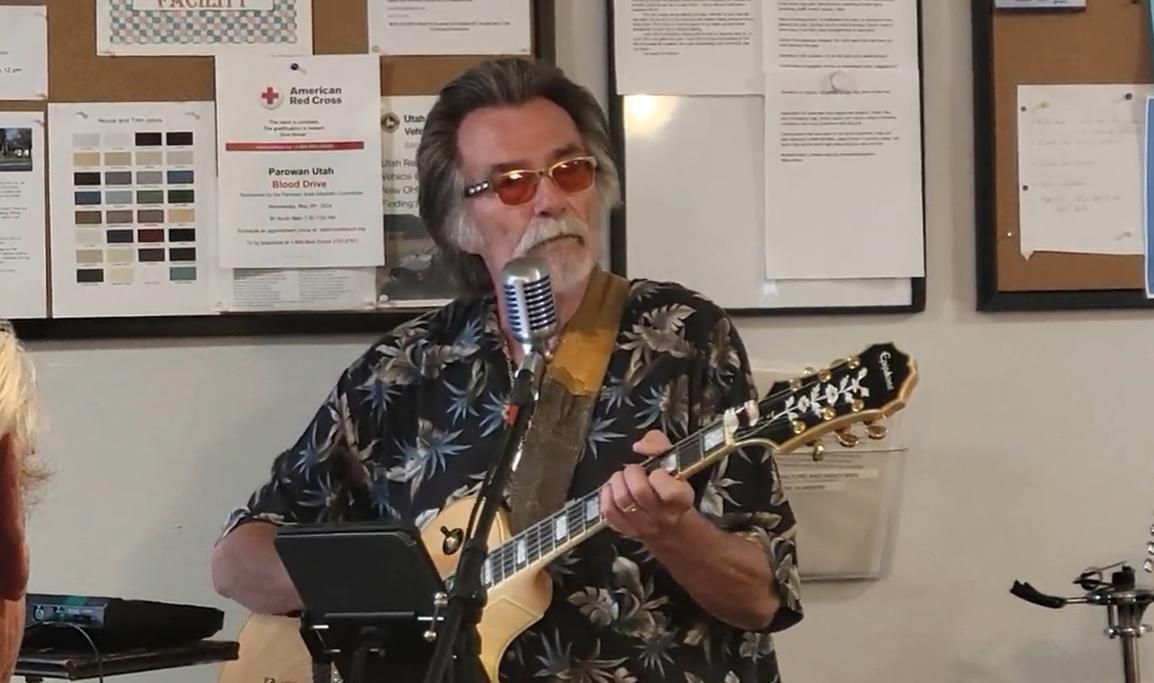 Kenny Laursen playing guitar and singing into a vintage microphone