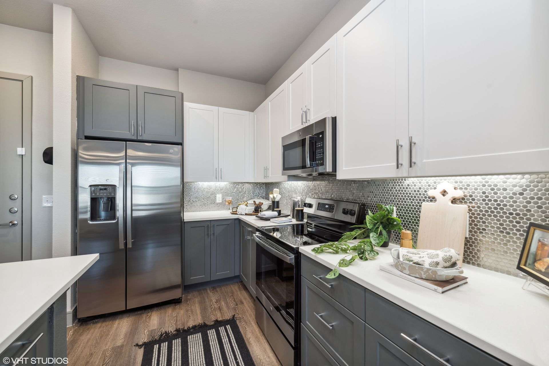 Modern kitchen with white cabinets, stainless steel appliances, gray lower cabinets, and mosaic backsplash