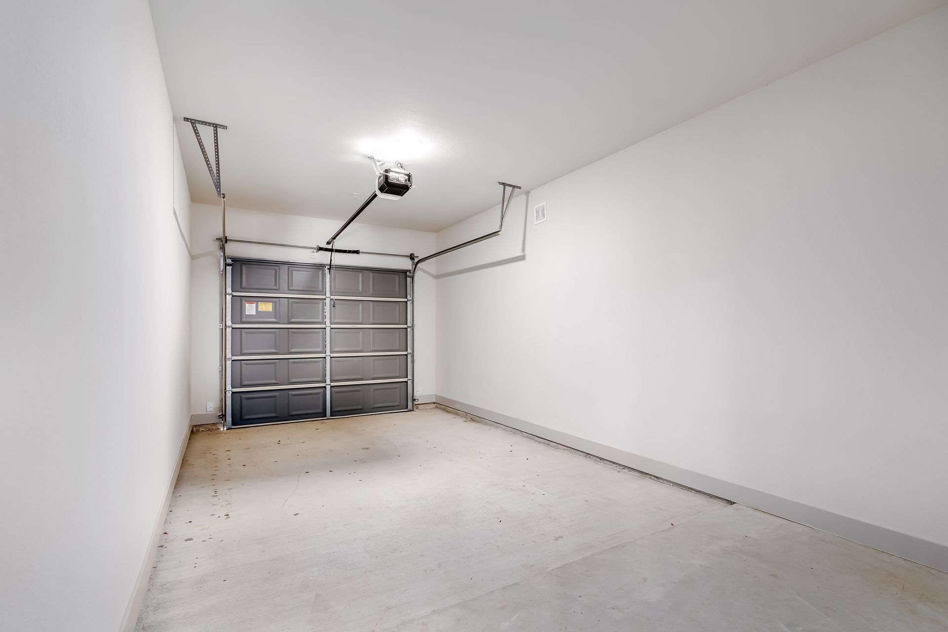 Empty white garage interior with closed double door and concrete floor