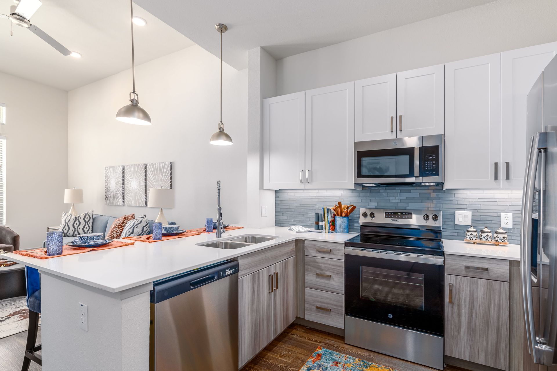 Bright modern kitchen with white cabinets, stainless appliances, and a white island under pendant lights
