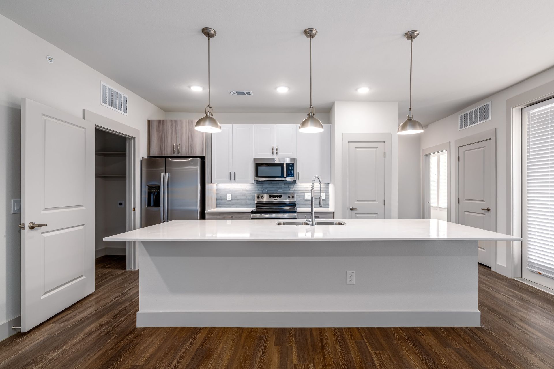 Bright modern kitchen with white island, stainless appliances, and wood floors.